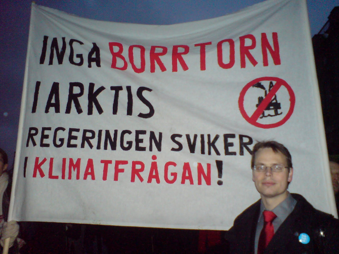 Max Andersson framför en banderoll med texten 'Inga Borrtorn i Arktis. Regeringen sviker i klimatfrågan!'